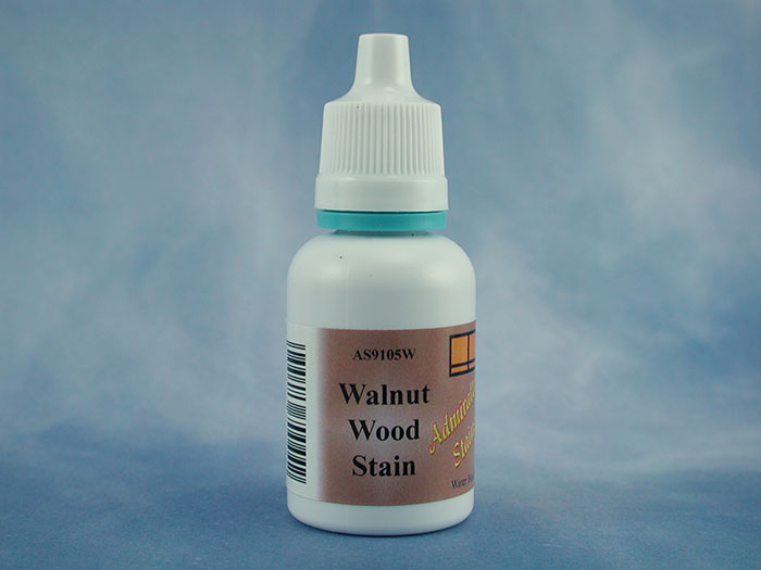A small white plastic bottle of Walnut Wood Stain with a white cap and a brown label, set against a mottled blue background.