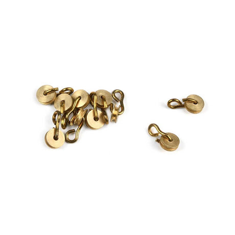 A set of small round gold-toned metal clasps or hooks, with one loose clasp placed to the right of a small pile of several clasps, photographed on a plain white background.